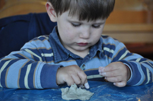 Junge bastelt mit Knetmasse 300